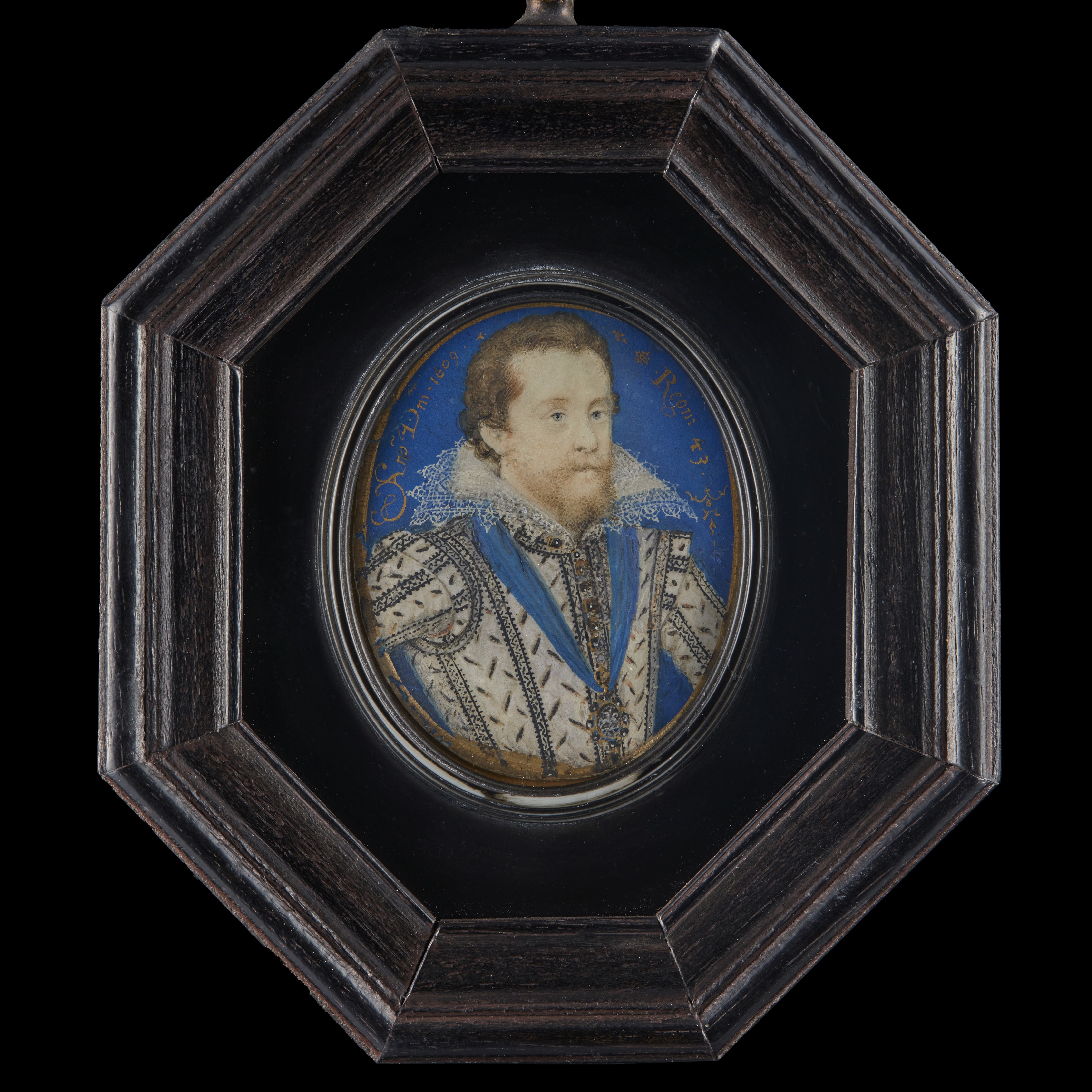 King James I of England and VI of Scotland (1566-1625), in white doublet, slashed on bodice and sleeves to reveal black, jewel-set gold buttons, white lace upstand collar, wearing the Lesser George of the Order of the Garter on a blue ribbon around his neck; blue background with gold border, inscribed in gold in the blue background 'Ano Dmni 1609 / Regni 43'